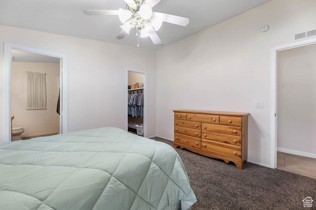 Carpeted bedroom with a spacious closet, a closet, ensuite bathroom, and ceiling fan