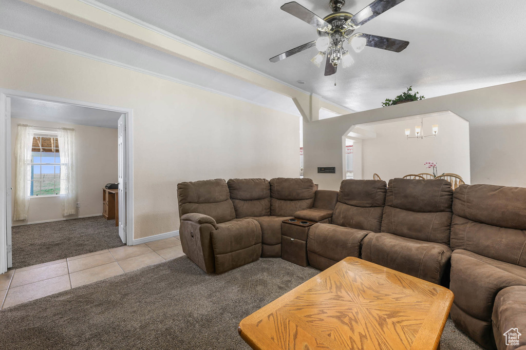 Living area featuring light colored carpet, light tile patterned floors, a ceiling fan, a chandelier, and arched walkways