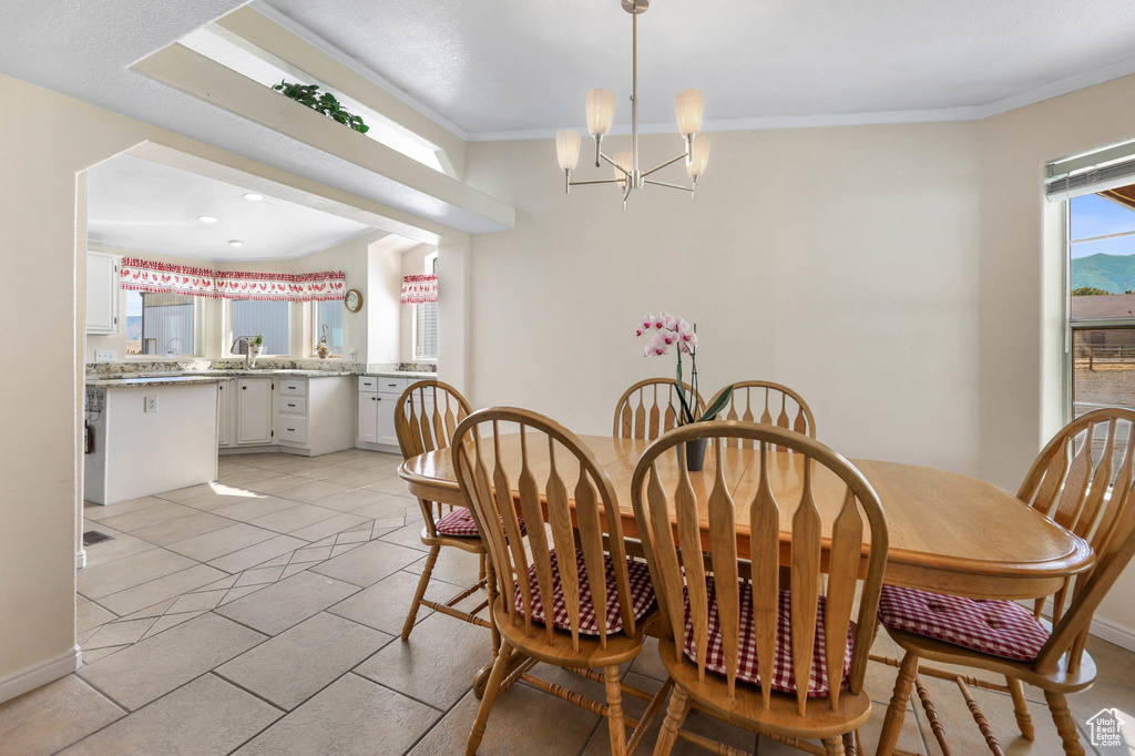 Dining space with a chandelier, crown molding, and light tile patterned floors