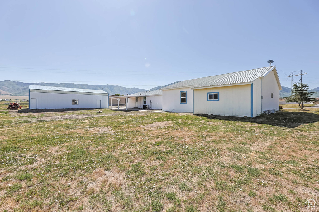 Back of house with a mountain view, a metal roof, and a yard
