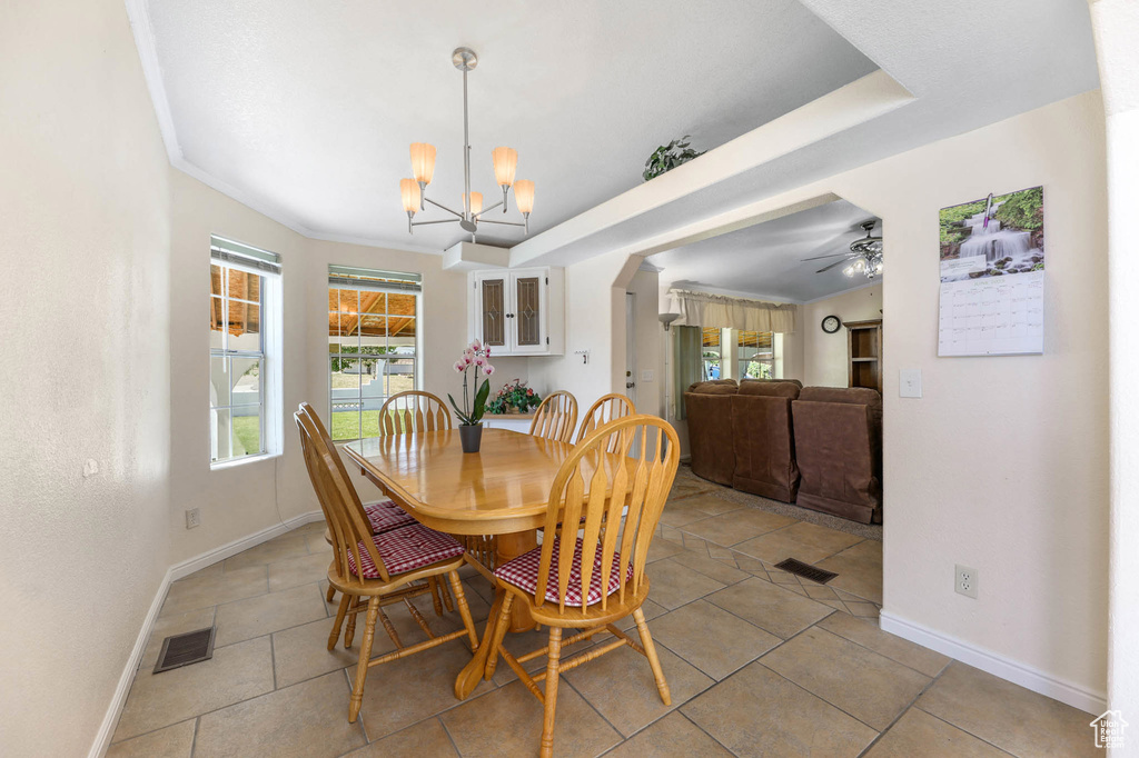 Dining room with a chandelier, light tile patterned flooring, and a ceiling fan