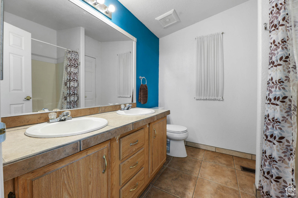 Bathroom with double vanity, tile patterned flooring, and a shower with shower curtain