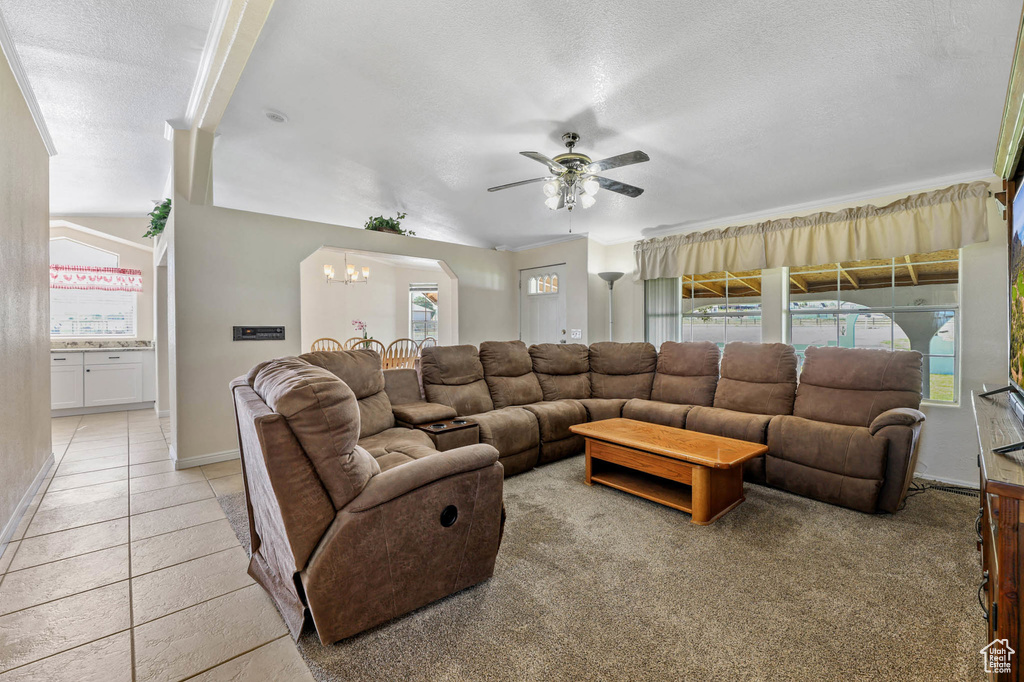 Living area with a ceiling fan, plenty of natural light, a chandelier, a textured ceiling, and light tile patterned floors
