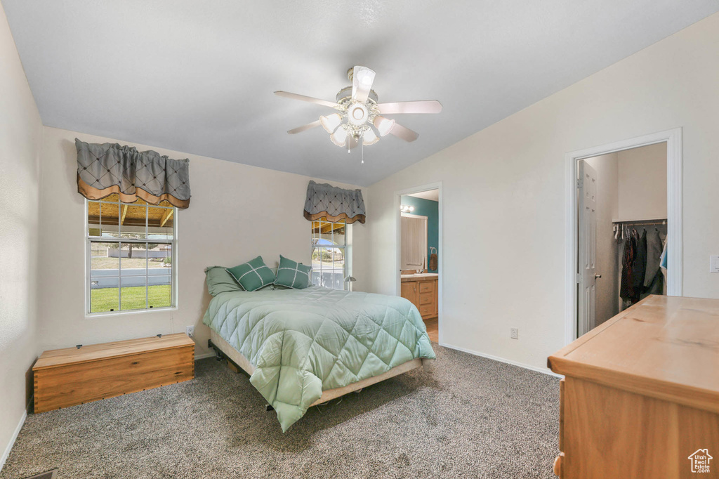 Carpeted bedroom with a walk in closet, ensuite bathroom, vaulted ceiling, a ceiling fan, and a closet