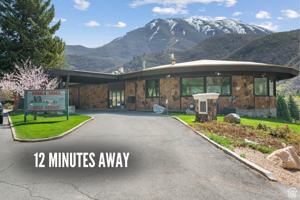 View of front of home featuring stone siding, a mountain view, and driveway