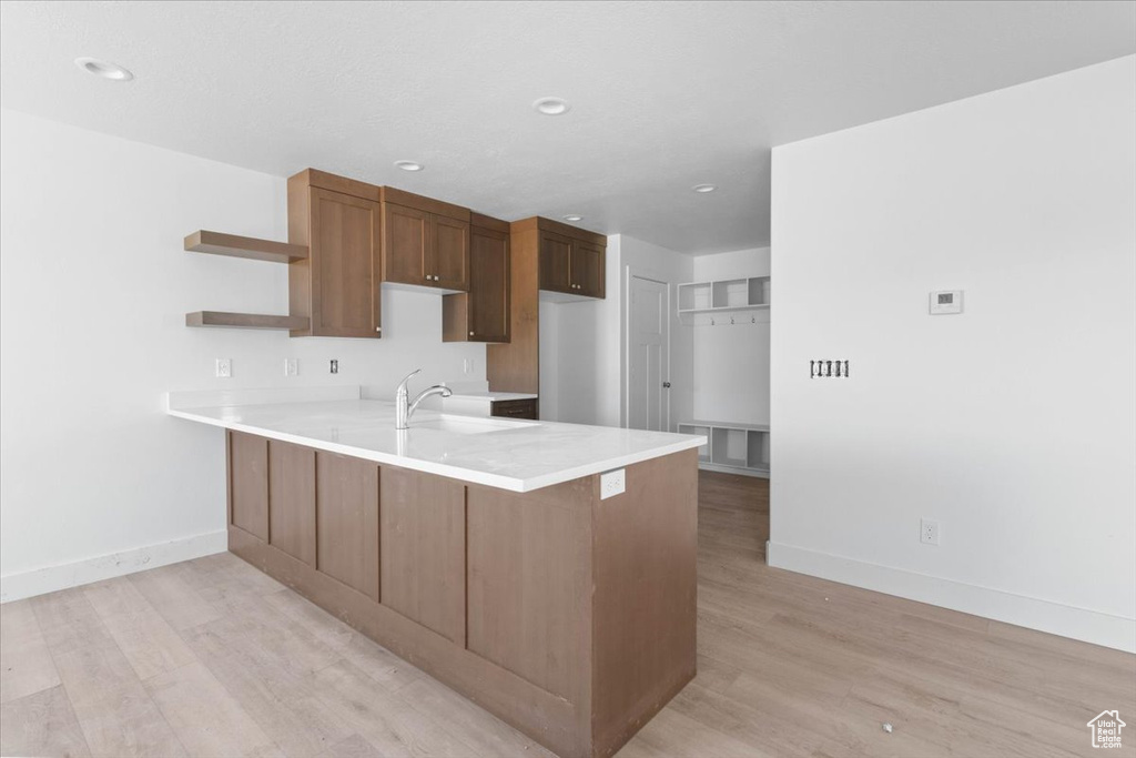 Kitchen with a peninsula, open shelves, light wood-style flooring, light countertops, and recessed lighting
