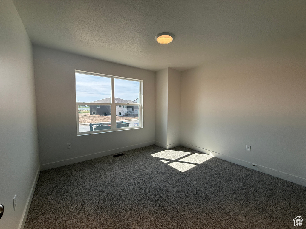 Empty room with carpet flooring and a textured ceiling