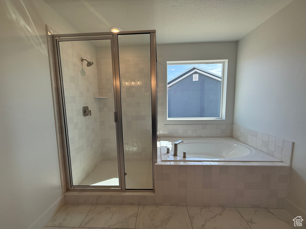 Bathroom with a bath, marble finish flooring, and a stall shower