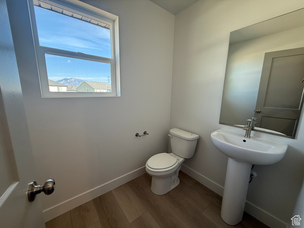 Half bathroom with toilet and wood finished floors