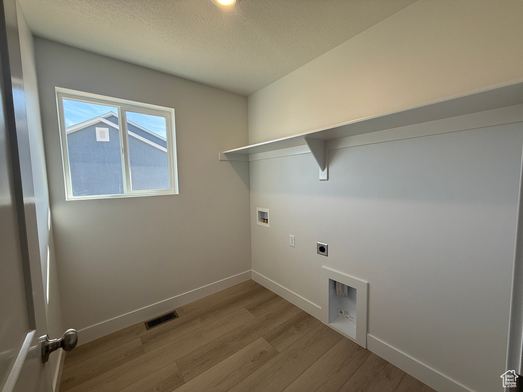 Laundry area featuring washer hookup, electric dryer hookup, wood finished floors, and a textured ceiling