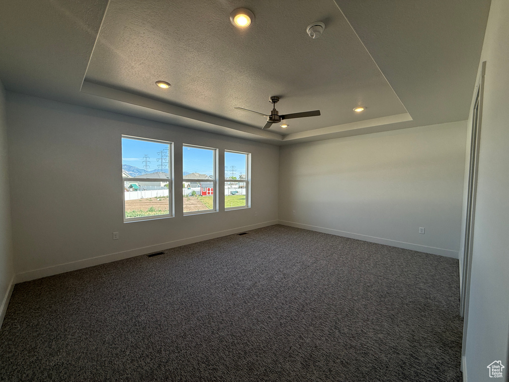 Carpeted spare room featuring a tray ceiling, a ceiling fan, recessed lighting, a textured ceiling, and a smoke detector