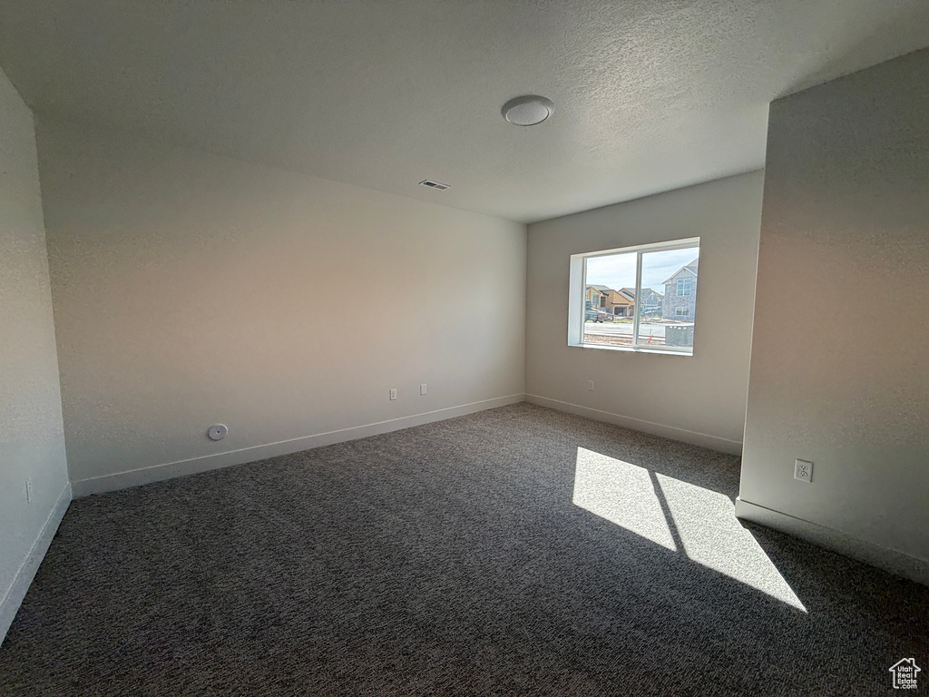 Carpeted spare room with baseboards and a textured ceiling