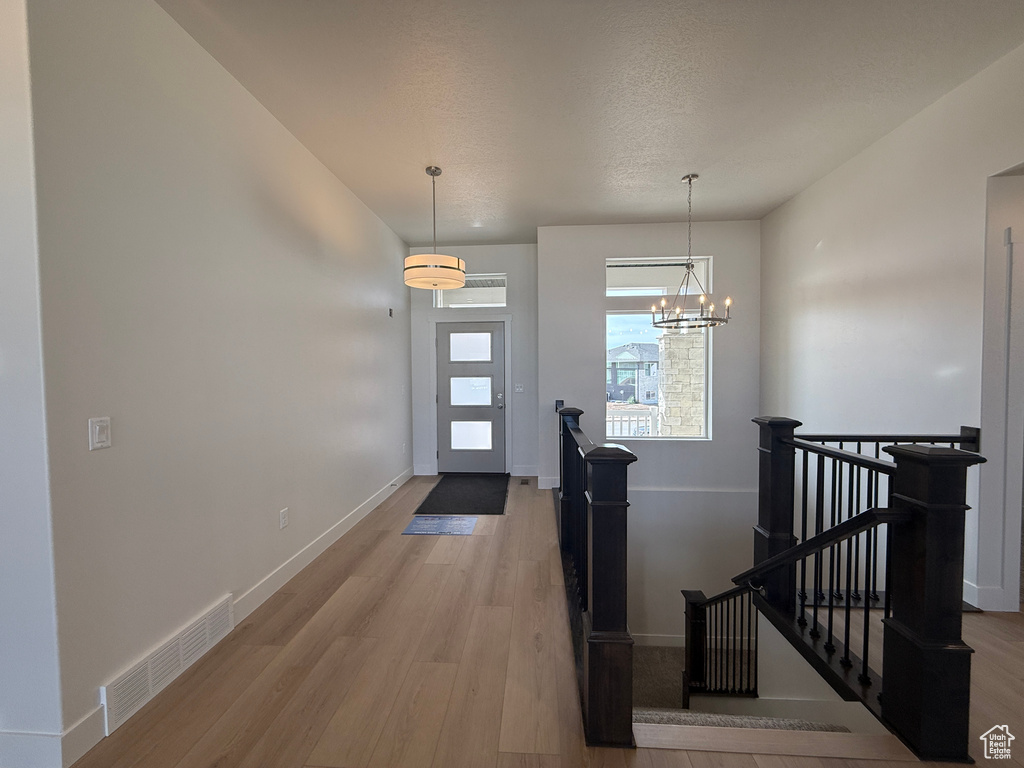 Foyer entrance with light wood-type flooring, a chandelier, and a textured ceiling