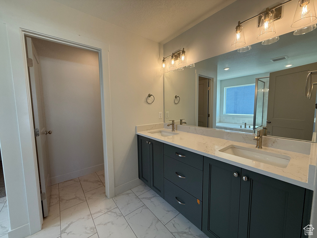 Full bathroom featuring double vanity and marble look tiles