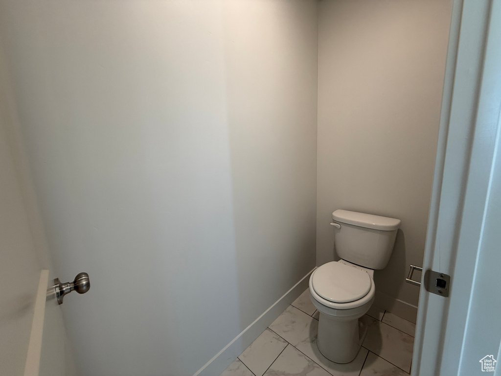 Bathroom featuring toilet and marble look tile flooring
