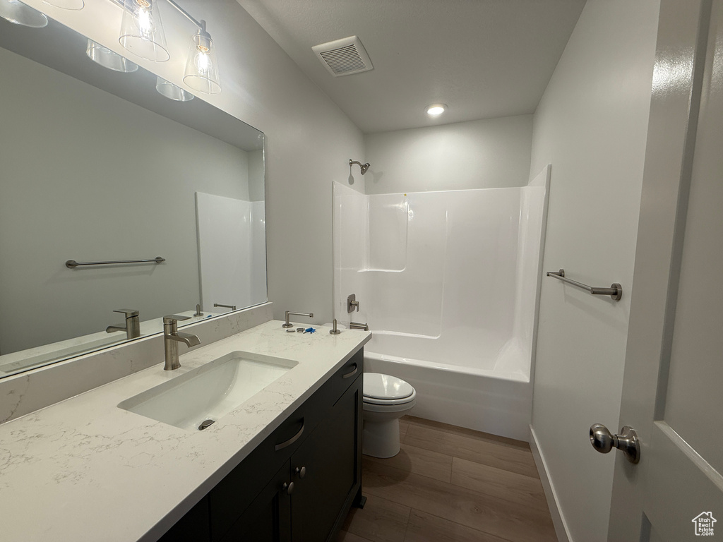 Full bath featuring wood finished floors, vanity, bathtub / shower combination, and recessed lighting