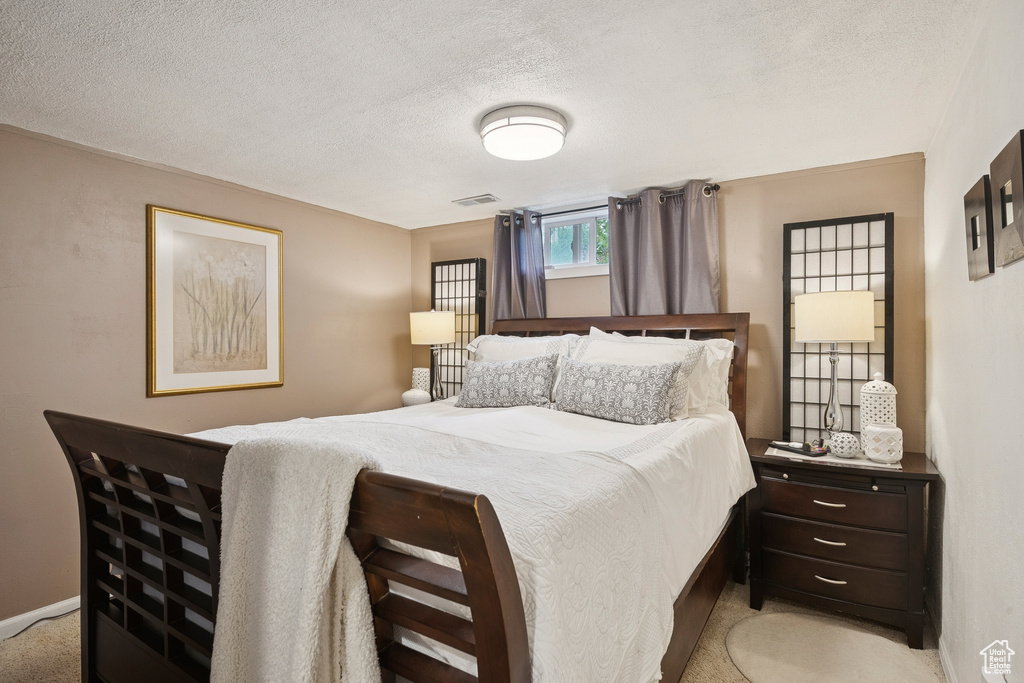 Bedroom with a textured ceiling and light carpet