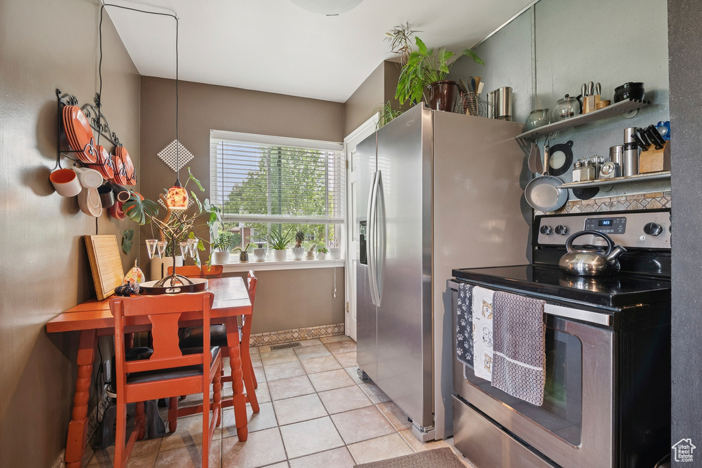 Kitchen with electric stove and light tile patterned floors