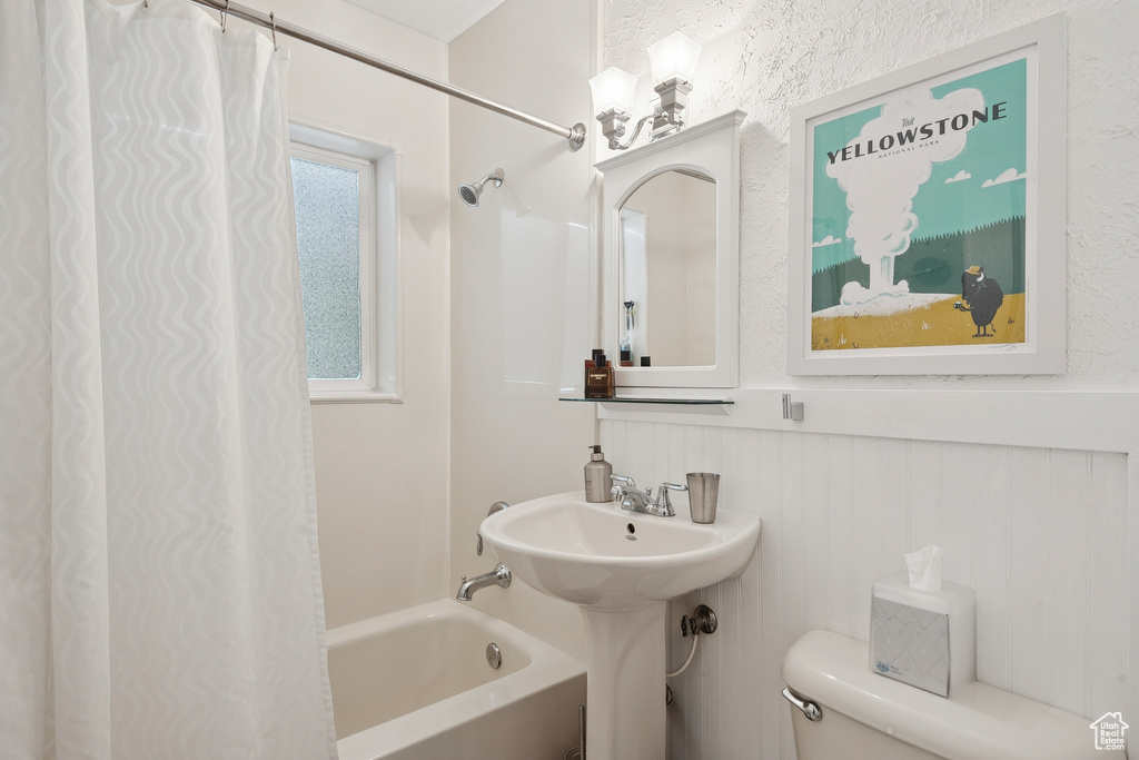 Bathroom with toilet and shower / bathtub combination with curtain