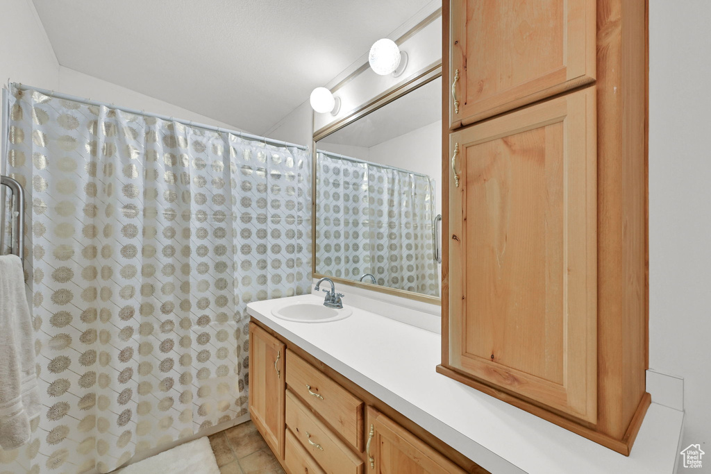 Bathroom with vaulted ceiling, vanity, tile patterned flooring, and a shower with shower curtain