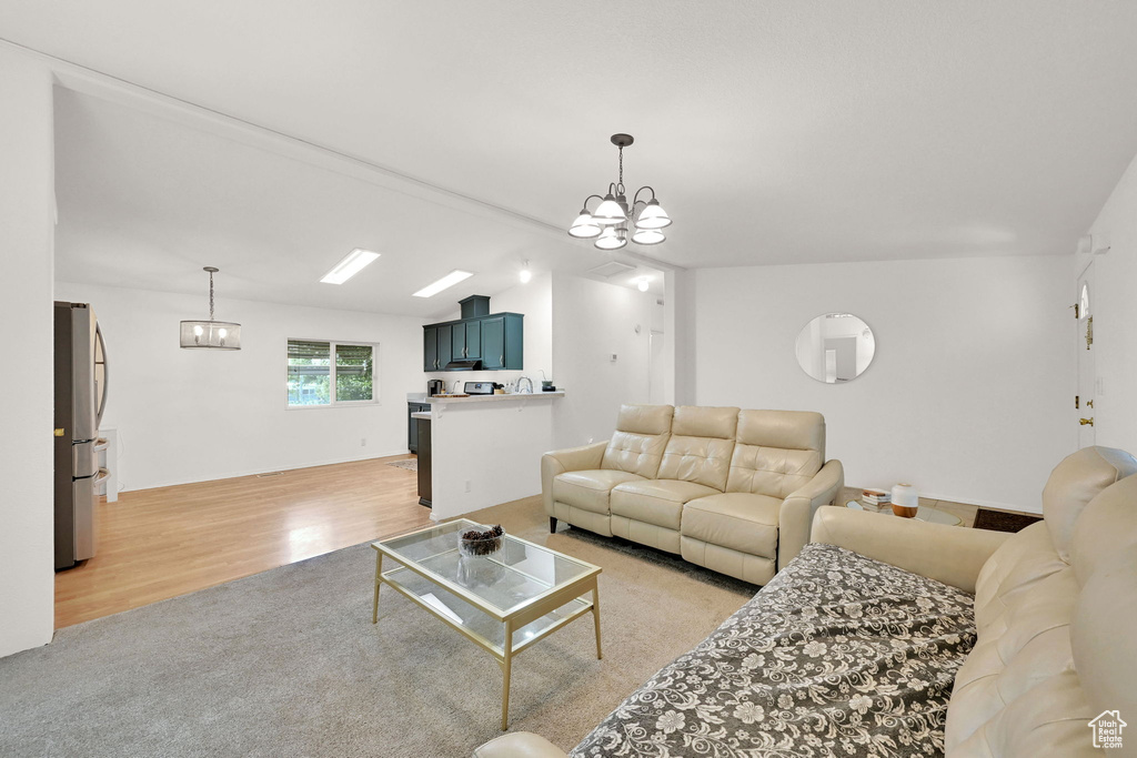 Living area featuring a chandelier, light wood finished floors, lofted ceiling, and light colored carpet