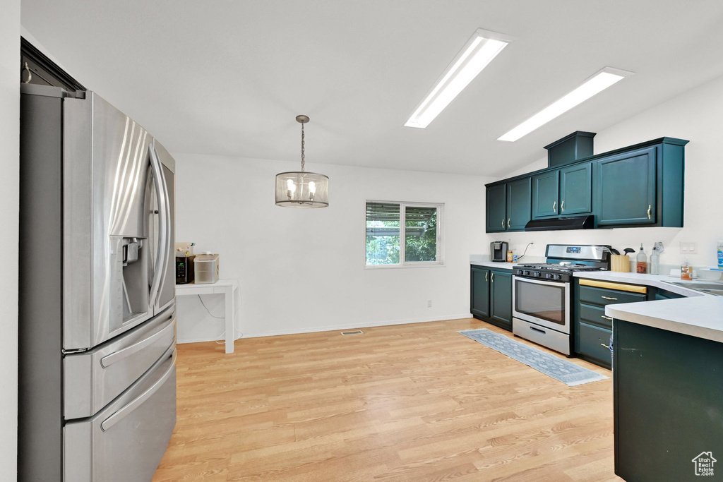 Kitchen featuring appliances with stainless steel finishes, under cabinet range hood, light countertops, light wood-style flooring, and vaulted ceiling