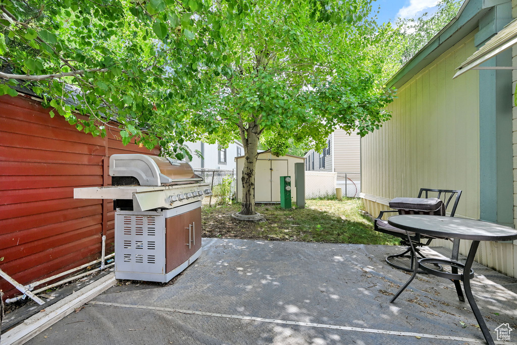 Fenced backyard featuring a storage shed, a grill, and a patio area