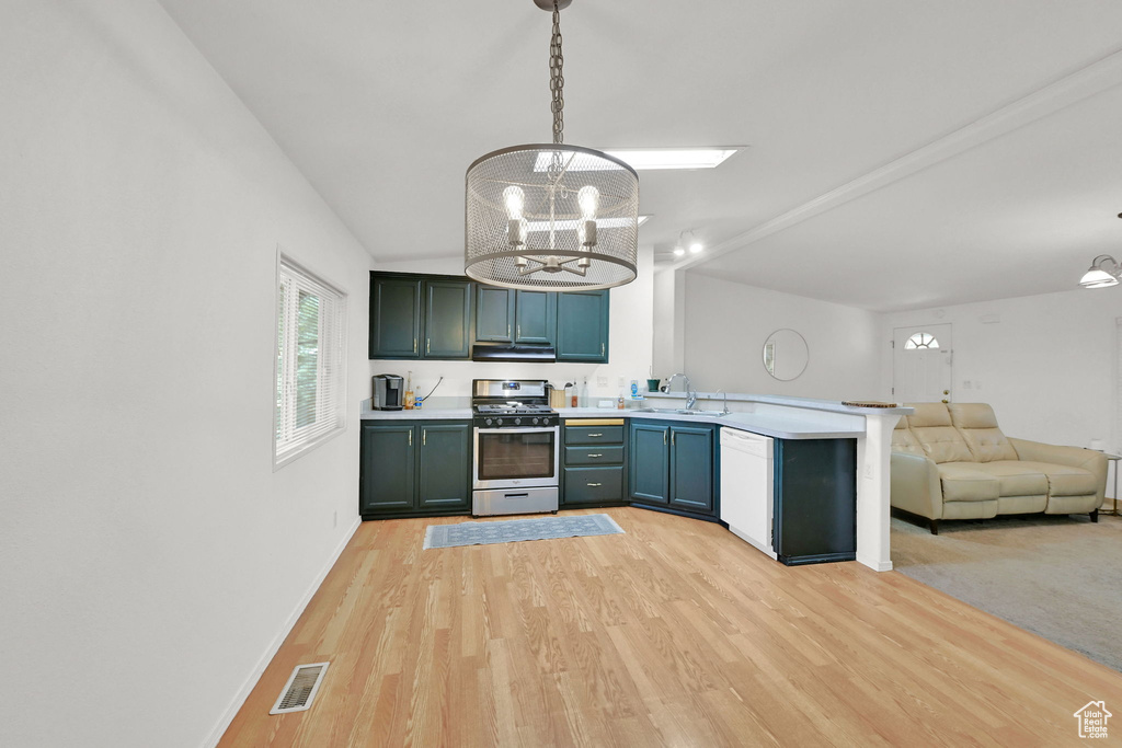 Kitchen with gas range, white dishwasher, a peninsula, a chandelier, and open floor plan