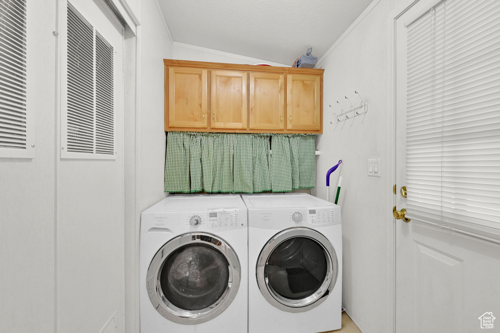 Laundry room featuring washing machine and dryer, ornamental molding, and cabinet space