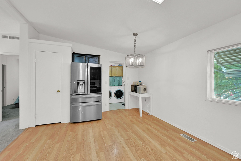 Kitchen with stainless steel fridge with ice dispenser, independent washer and dryer, a chandelier, light wood-style flooring, and vaulted ceiling