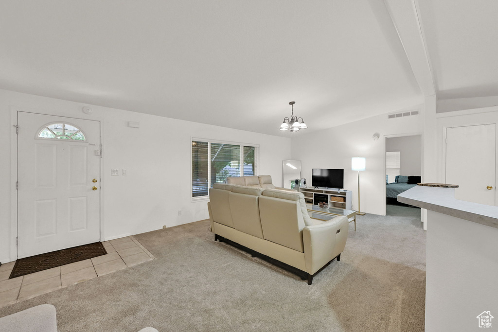 Living room featuring light carpet, a chandelier, vaulted ceiling, and light tile patterned flooring