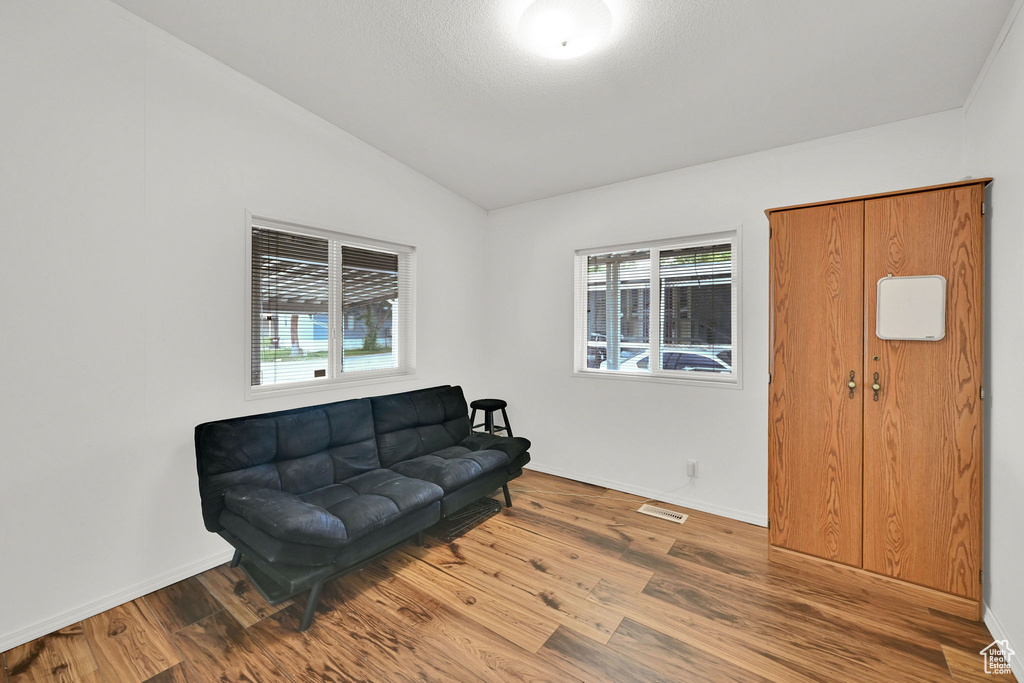 Sitting room with vaulted ceiling, healthy amount of natural light, and wood finished floors
