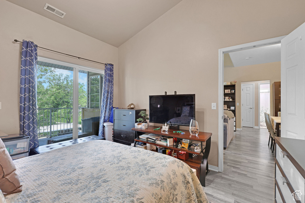 Bedroom with access to outside, light wood finished floors, and high vaulted ceiling