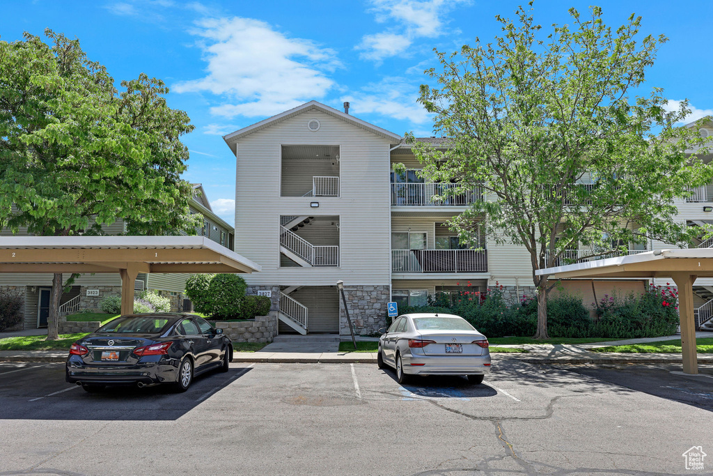 View of property featuring covered and uncovered parking
