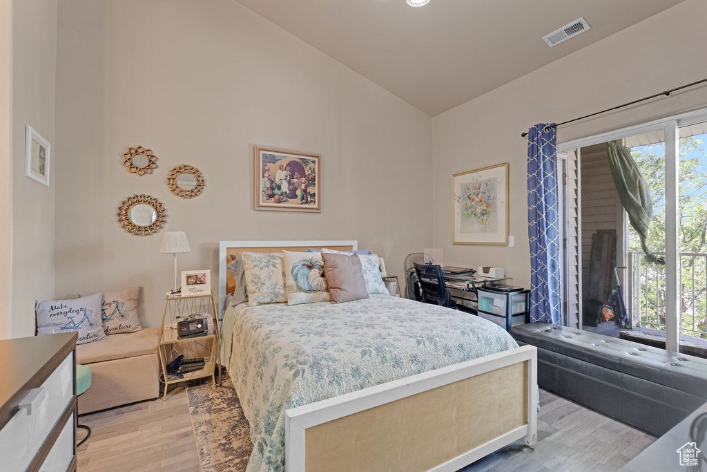 Bedroom with light wood-style flooring and high vaulted ceiling