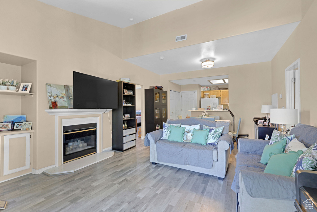 Living room with light wood finished floors and a glass covered fireplace