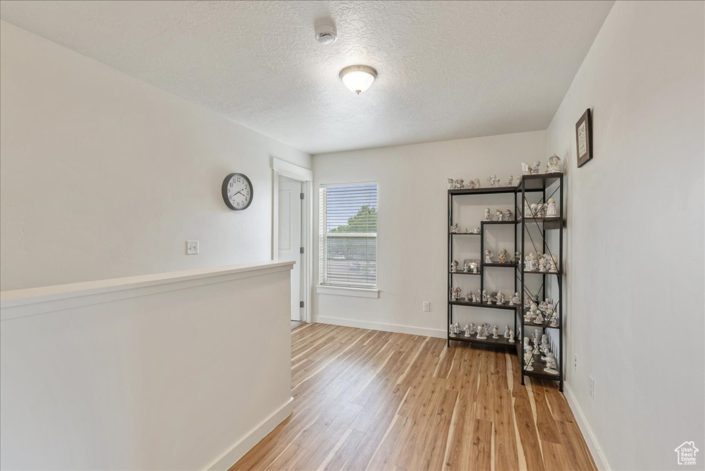 Unfurnished room with a smoke detector, light wood-type flooring, and a textured ceiling