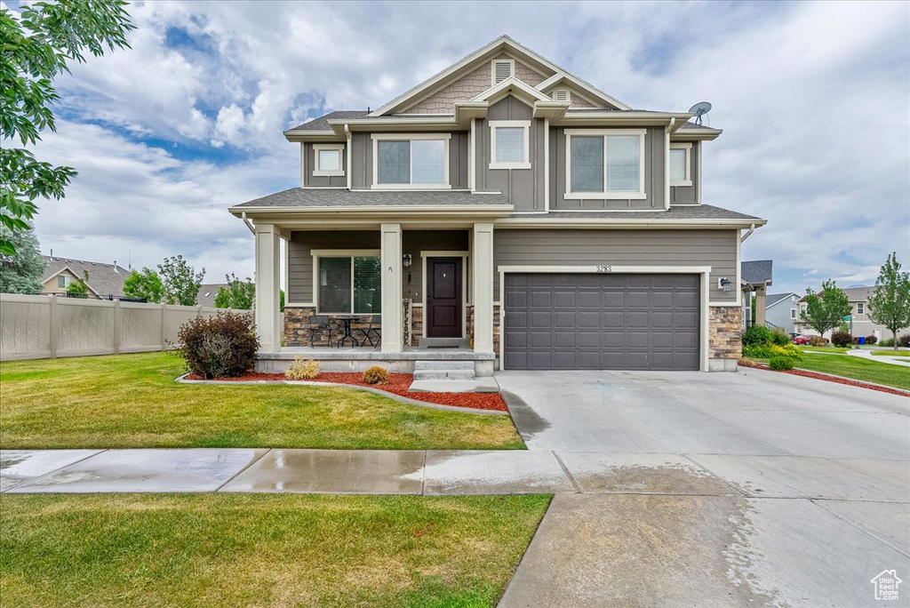 View of front of house with an attached garage, board and batten siding, concrete driveway, stone siding, and a porch
