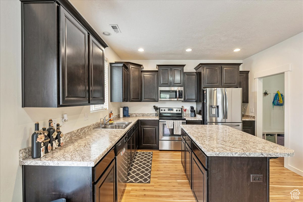 Kitchen with stainless steel appliances, a center island, light wood finished floors, light countertops, and recessed lighting