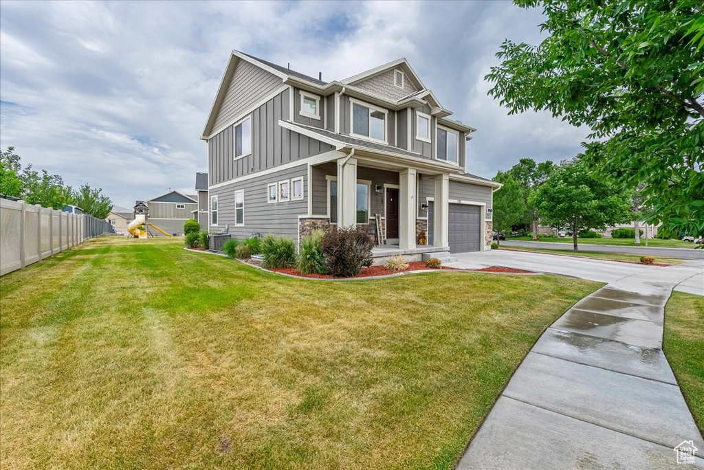 Craftsman-style house with driveway, board and batten siding, an attached garage, a playground, and a porch