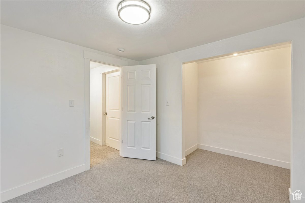 Empty room featuring light carpet and baseboards