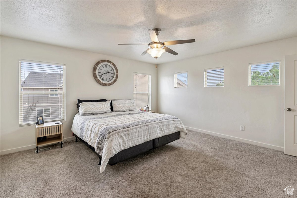 Bedroom with light colored carpet, a textured ceiling, and ceiling fan