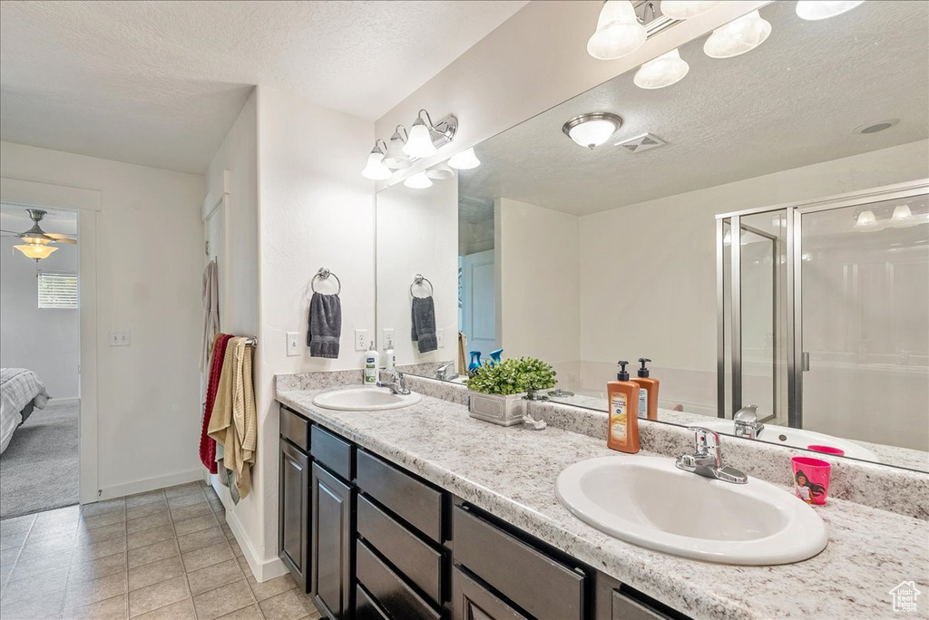 Full bathroom featuring ensuite bathroom, double vanity, a shower stall, a textured ceiling, and tile patterned flooring