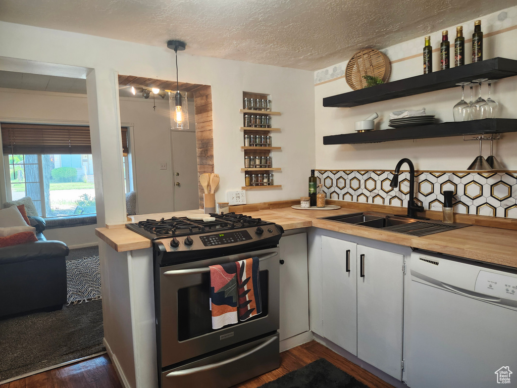 Kitchen featuring wooden counters, dishwasher, stainless steel gas range, open shelves, and dark wood finished floors