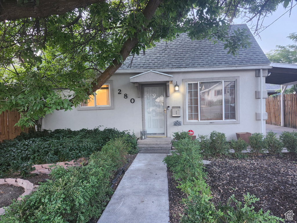 View of front facade with stucco siding and roof with shingles