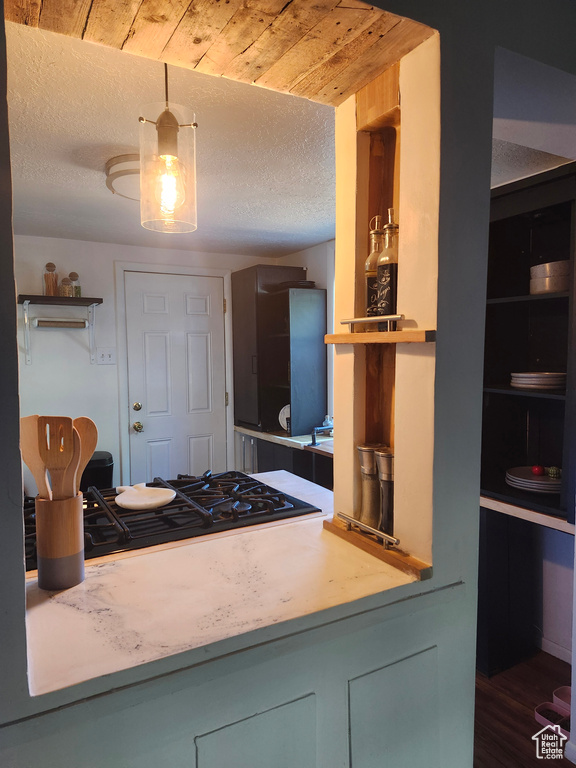 Kitchen featuring black gas stovetop, a textured ceiling, light countertops, and wood finished floors