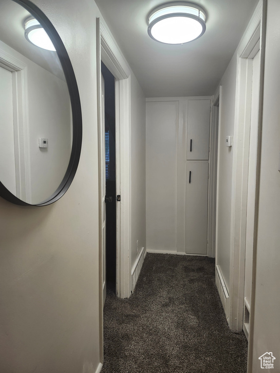 Corridor featuring dark colored carpet and baseboards