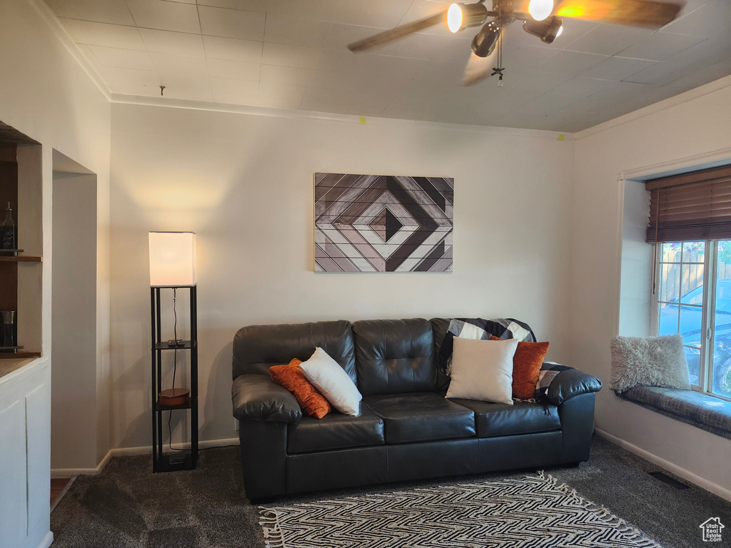 Carpeted living room with ceiling fan and crown molding