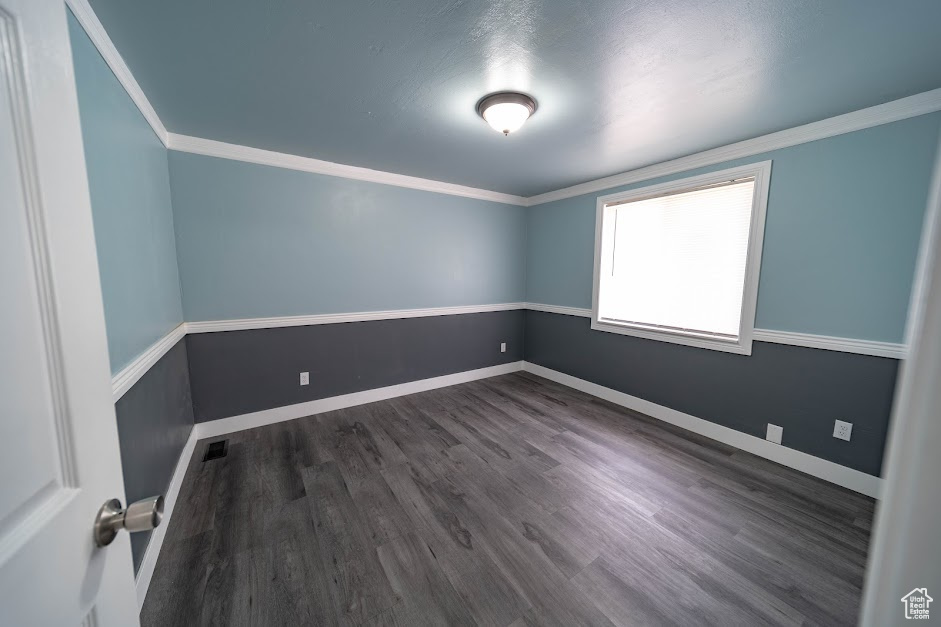 Unfurnished room with dark wood-style floors and crown molding