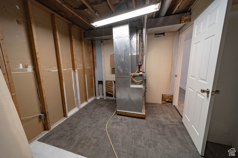 Unfinished basement with carpet and heating unit